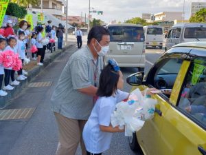 「交通ルールを守ってね」とチョコレートをプレゼントする参加者ら＝13日、袖山入り口交差点