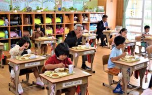 児童たちと一緒に給食を食べる座喜味市長（中央）＝17日、伊良部島小中学校