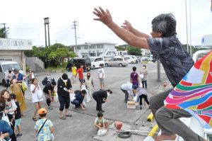 「進水式」で船上からお菓子などを「オオバンマイ」する山口船長（右）＝10日、池間漁港