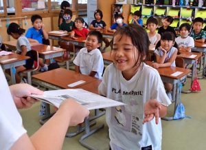 夏休みを心待ちにしていた１年生が初めての「よい子のあゆみ」を受け取り笑顔になった＝20日、南小学校