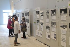 展示された池間島、佐良浜の祭祀の様子を捉えた写真に見入る市民ら＝8日、市未来創造センター中央公民館ギャラリー