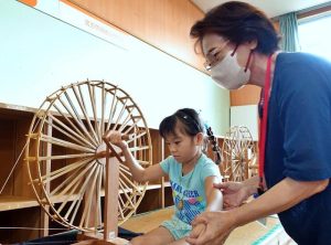 講座最終日は参加者たちが糸車で糸によりをかける作業を体験した＝９日、市歴史文化資料館