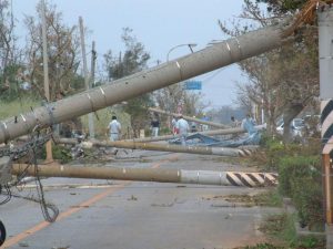 強風で道路に倒れた電柱の撤去に向けて作業を行う関係者ら＝2003年9月12日、県道78号線（城辺線）