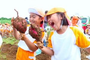 大きなイモを手に笑顔を見せた園児たち＝19日、上野新里の畑