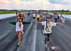 秋風に吹かれ、朝日を浴びながら滑走路を歩く参加者ら＝23日、宮古空港