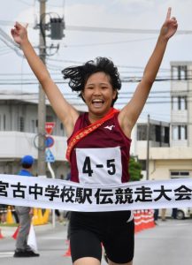 喜びを爆発させる平良のアンカー・友利涼＝28日、市陸上競技場前