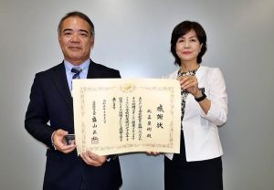 比嘉さん（左）が文部科学大臣感謝状を受けたことを大城教育長に報告した＝30日、市役所