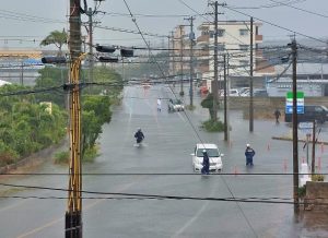 大雨による冠水で立往生した車両に消防職員が対応する様子が見られた＝４日、ファミリーマート宮古工業高校前店近く