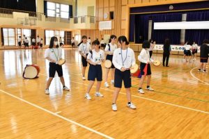 エイサーの体験を通して交流を深める両校の生徒たち＝18日、伊良部島小・中学校体育館