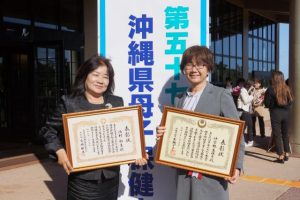 県母子保健大会で県知事表彰の仲宗根さん（右）と、大会長表彰の池村さん＝18日、沖縄市