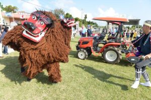 ２頭の獅子が農機具の厄払いを行った＝29日、比嘉公民館前