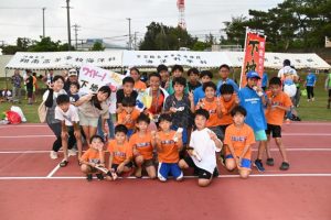 子供たちと一緒にゴールした下地さん（中央）＝14日、市陸上競技場