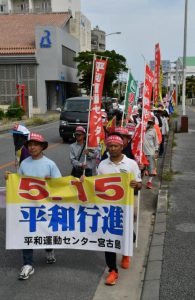 横断幕を持って行進する参加者ら＝１１日、平良西里