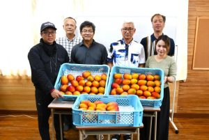 川満さん（前列右）から屋嘉比代表（同右から2人目）らにマンゴーが贈られた＝13日、サシバ教室