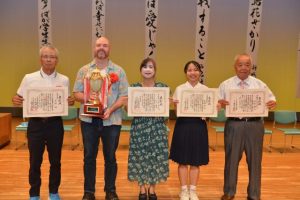 （写真右から）審査員特別賞の川満さん、文化協会長賞の西銘さん、市長賞の園江さん・マイケルさん夫妻、教育長賞の友利さん＝14日、マティダ市民劇場