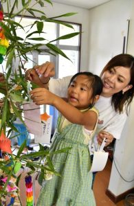  短冊などを飾り付ける親子＝７日、川満団地集会場