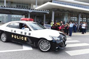 座喜味市長や子どもたち、関係者が見守る中、パレードに出発する車両＝13日、市役所