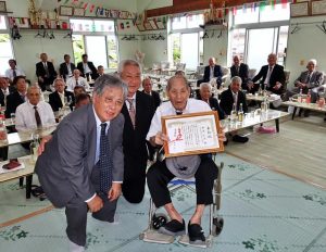 今年、数え１００歳を迎えた新崎玄次さん（手前右）に表彰状が贈呈された＝28日、前里ムトゥ