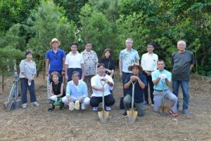 植樹を行った安藤会長（前列中央）ら東京高輪ロータリークラブの会員と下地会長（前列右から２人目）＝15日、平良宮原地区の竹林公園