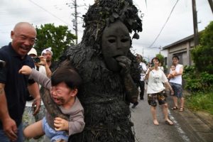 パーントゥに抱きかかえられて泣き叫ぶ幼児＝８日、平良島尻