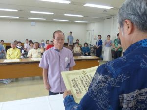 西銘氏の代理で衆院選当選証書を受け取る古堅後援会長＝30日、県庁