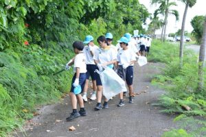 サシバ保護月間にちなみ道路脇のごみを拾い集める児童生徒たち＝17日、伊良部長浜