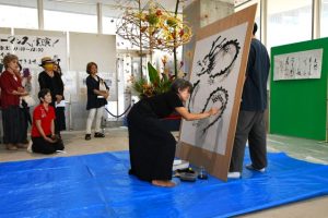 龍の墨絵を描くマキャンさん＝12日、市未来創造センター