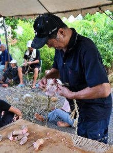 豚の骨を縄に縛り付ける住民＝７日、島尻