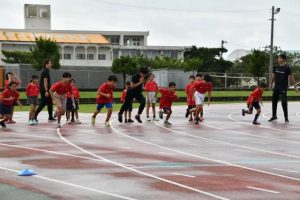 戸邉さん（右）の指導を受け、走り出す子どもたち＝16日、市陸上競技場