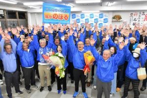 初当選を果たし支持者らと共に万歳する嘉数登氏（中央）＝19日、平良西里の嘉数登氏選対本部