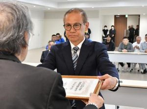 市選挙管理委員会の仲間委員長から当選証書を受け取る嘉数氏＝22日、市役所