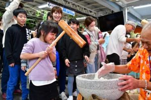 笑顔で餅つきに挑戦する女の子＝３日、島の駅みやこ